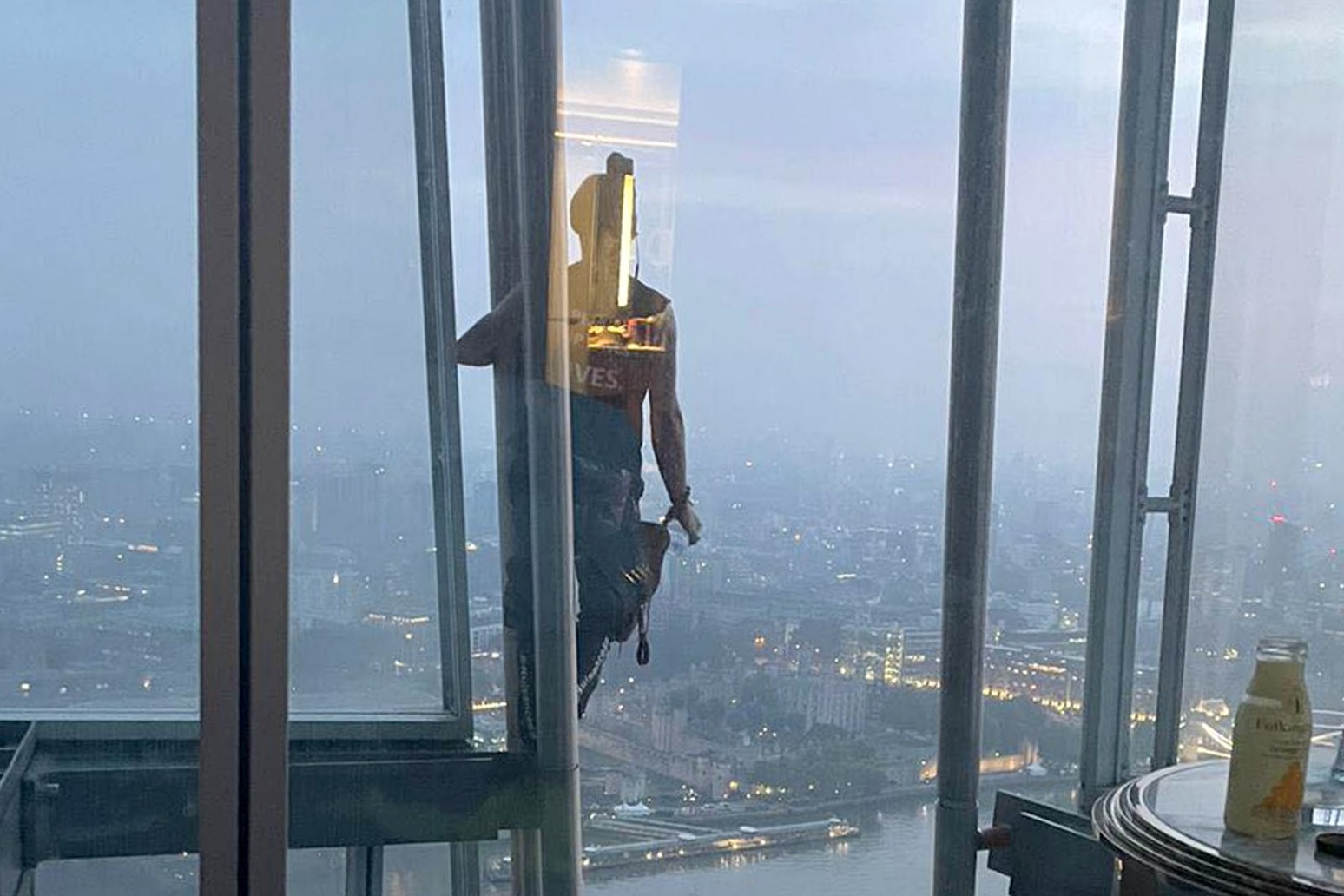 Couple wave at barefoot man climbing past their window at the Shard 40 floors up 